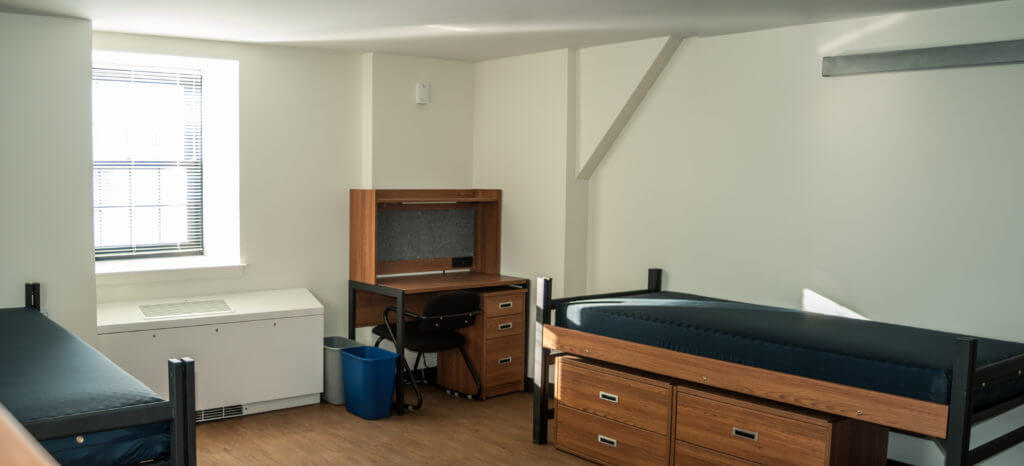 Clean dormitory with two beds and a desk