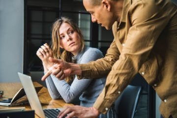 Two people look over a report on a computer