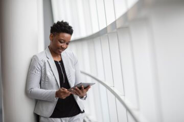 Woman looking down at tablet in a clean building. Photo by Emmy E from Pexels.