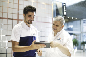 Two Impact employees, both wearing company shirts, look at information on a tablet together.