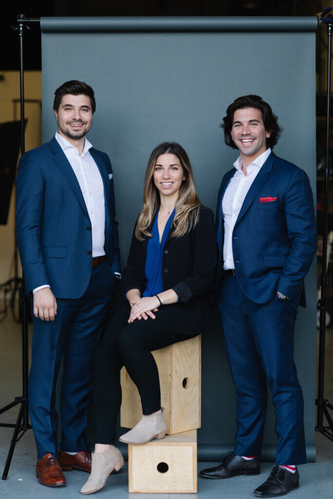 Yiannis Boutsalis, Georgia Corsetti, and George Boutsalis pose for a portrait, dressed in suits.