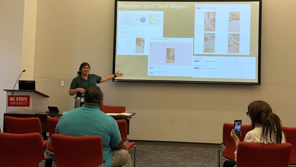 Kelly Freshcorn giving a presentation, with the slides showing screenshots of employee spot check inspections done in OrangeQC.