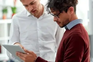 A photo of a contractor and a client discussing a janitorial PR report that captures the client’s feedback on the cleaning team’s service, referenced above.